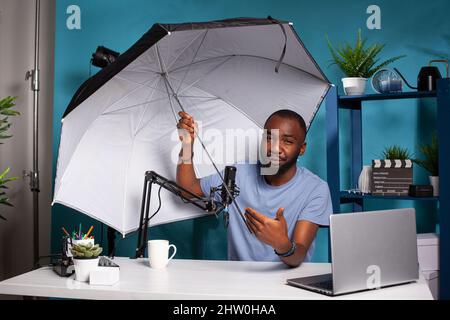 Technologieprüfer testet Blitzreflektorschirm, der Größe und Vorteile für Live-Vlog-Übertragungen präsentiert. Professioneller Fotograf vlogger Überprüfung Fotografie Studio Ausrüstung in Live-Podcast. Stockfoto