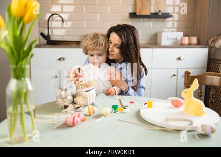 Schöne Mutter und ihr Sohn mit weißen lockigen Haaren bereiten sich auf Ostern vor Stockfoto