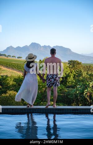 Ein Paar Männer und Frauen im Schwimmbad mit Blick auf die Weinberge und Berge von Stellenbosch Südafrika. Stockfoto