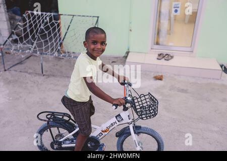 Maafushi, Malediven - 25. Juni 2021: Lächelnde Einheimische Kinder spielen auf den maledivischen Straßen Stockfoto