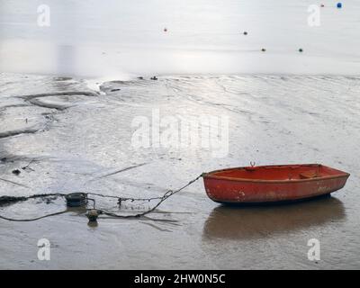 Kleines rotes, zartes Ruderboot, auf Schlamm, Gezeiten. Stockfoto