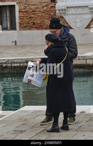 Ein älteres Paar, das sowohl alte als auch neue Technologien verwendet, um sich in Venedig zurechtzufinden Stockfoto