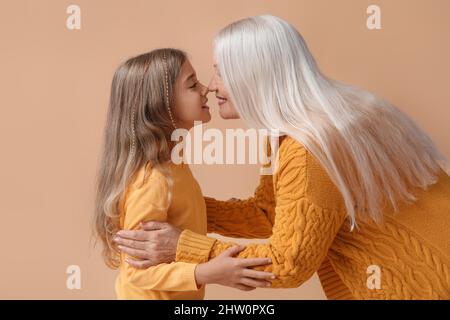 Kleines Mädchen mit ihrer Oma, die Nasen auf beigem Hintergrund berührt Stockfoto