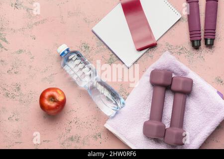 Stilvolle Sportausrüstung und Apfel auf rosa Grunge Hintergrund Stockfoto