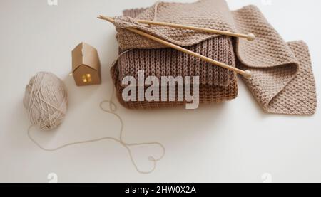 Stricknadeln mit Faden, beigefarbenes Garn. Hobby für Frauen Konzept. Strickzubehör. Stockfoto