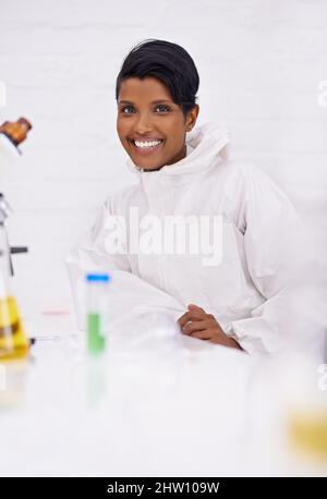 Ein erfüllender Beruf. Ein Porträt einer glücklichen jungen Wissenschaftlerin, die in ihrem Labor sitzt. Stockfoto
