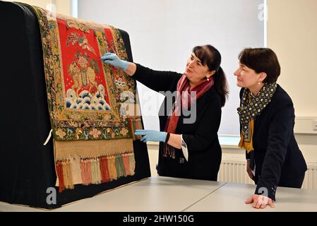 03. März 2022, Thüringen, Gotha: Marie-Luise Gothe (l.), Textilrestauratorin, und Kerstin Volker-Saad (r.), wissenschaftliche Projektleiterin, betrachten eine Satteldecke, die Prinz Raden Saleh von Java einst Herzog Ernst II. Von Sachsen-Coburg und Gotha geschenkt hat. Mehrere Objekte werden bei einer Presseveranstaltung zum Abschluss des Projekts „Dialog der Welten“ ausgestellt. Indizierung der Ethnographica.' Nach anderthalb Jahren hat die Stiftung Schloss Friedenstein Gotha im Rahmen des Projekts "Gotha Transdigital" die "vorbildliche Indizierung von Ethnographica in der Sammlung Schloss Friedenstein Gotha" abgeschlossen Stockfoto