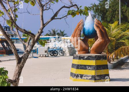 Maafushi, Malediven - 25. Juni 2021: Lokales Denkmal mit gefalteten Händen und Blue Water Drop an der Maafushi Straße Stockfoto