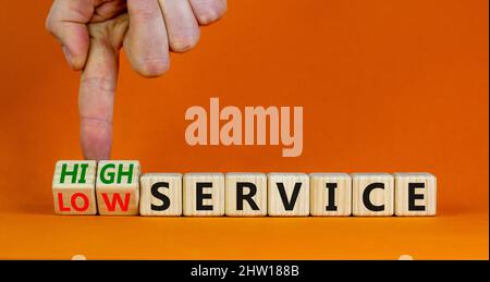 Symbol für niedrigen oder hohen Service. Geschäftsmann dreht Würfel und ändert Wörter niedrigen Service zu hohem Service. Schöne orange Tisch orange Hintergrund. Unternehmen Stockfoto