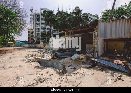 Ruinen der Holzhäuser mit dem maledivischen Hotelgebäude im Hintergrund, Maafushi Island Stockfoto