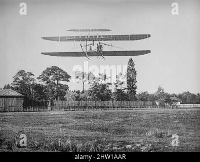 Ein Foto aus dem frühen 20.. Jahrhundert der Wright Machine im Flug. Erfunden und entwickelt von den Gebrüdern Wright, Orville und Wilbur Wright, haben die amerikanischen Luftfahrtpioniere im Allgemeinen das erste erfolgreiche motorbetriebene Flugzeug der Welt geflogen. Am 17. Dezember 1903, 4 Meilen (6 km) südlich von Kitty Hawk, North Carolina, machten sie mit dem Wright Flyer den ersten kontrollierten, anhaltenden Flug eines angetriebenen, schwereren Flugzeugs als der Luft in den heutigen Kill Devil Hills. Die Brüder waren auch die ersten, die Flugzeugsteuerungen erfanden, die Flug mit festem Flügel möglich machten. Stockfoto