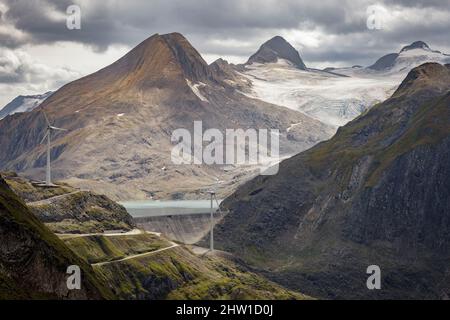 Schweiz, Kanton Tessin, Ulrichen, Nufenenpass, Gries-Staudamm, Zwei Windkraftanlagen in ihrer Bergumgebung, Standort des höchsten Windparks Europas, 2500 Meter über dem Meeresspiegel, Blick auf den Arbola Peak (Ofenhorn, 3235m), im Hintergrund, an der Grenze zwischen Italien und der Schweiz gelegen Stockfoto