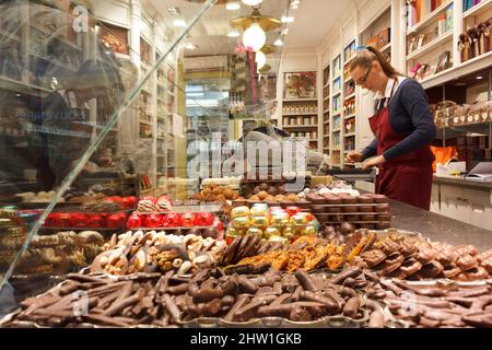 Belgien, Brüssel, rue de l'Etuve, Verkäuferin und Schaufenster eines Schokoladenladens Stockfoto