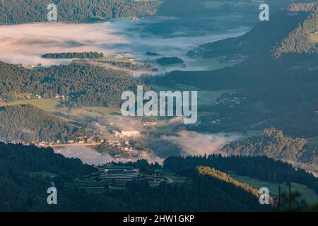 Deutschland, Bayern, Oberbayern, Berchtesgaden, Obersalzberg, Nebliger Sonnenaufgang über dem luxuriösen Kempinski-Hotel und dem Golfplatz, der den Berghof, Hitlers ehemaliges Hauptquartier während des Zweiten Weltkriegs, ersetzt, im Hintergrund die Stadt Berchtesgaden Stockfoto