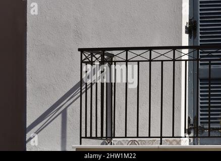 Altes neoklassizistisches Haus mit einem handgefertigten schmiedeeisernen Geländer an einer weißgetünchten Wand in Nafplio, Griechenland. Stockfoto