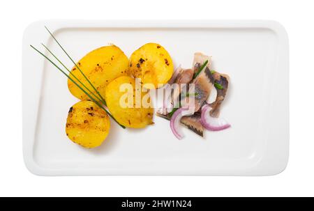Scheiben milder Heringe mit Kartoffeln und Zwiebeln auf dem Teller serviert Stockfoto