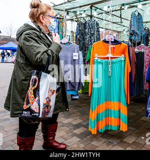 Epsom Surrey London, Großbritannien, März 03 2022, Frau allein stehend Browsing Fashion Clothing Market Stall trägt Protactive Covid-19 Gesichtsmaske Stockfoto