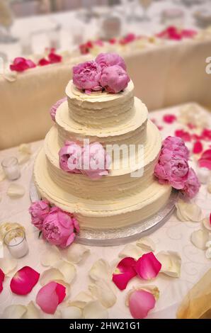 Eine elegante, mit Pfingstrosen verzierte Hochzeitstorte mit Schmetterlingsdesign Stockfoto