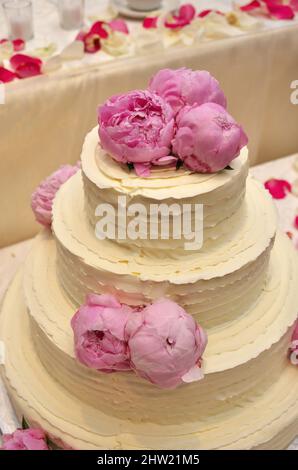 Eine elegante, mit Pfingstrosen verzierte Hochzeitstorte mit Schmetterlingsdesign Stockfoto