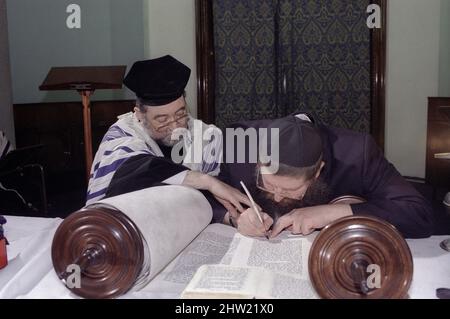 Rabbi Leonard Tann schreibt im vorletzten Brief auf die Tora-Schriftrolle. Der Oberrabbiner Jonathan Sacks war Ehrengast für die Aufnahme der letzten Briefe in eine neue Sefer-Torah in der Synagoge der hebräischen Kongregation Singers Hill am Sonntag, dem 15. März 1998. Mitglieder der Gemeinde sowie der Oberrabbiner fügten jeweils einen einzigen Brief hinzu. Stockfoto