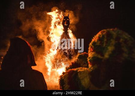 Macedo de Cavaleiros, Portugal. 28.. Februar 2022. Caretos führt religiöse Rituale während der Verbrennung der Zaubermaske während der Feier des Karnevals in Podence durch.im portugiesischen Dorf Podence, in der Gemeinde Macedo de Cavaleiros, tragen Männer während des Karnevals die traditionelle Tracht, die als "Caretos" bekannt ist, Tragen Sie Masken aus Messing oder Holz und tragen Sie bunte Wollkostüme. Sie schreien und jagen Menschen auf den Straßen, um sie zu verjagen, insbesondere alleinstehende Frauen. Caretos de Podence wurde am 2019. Dezember von der UNESCO zum immateriellen Kulturerbe der Menschheit erklärt. Die Veranstaltung endet mit der BU Stockfoto