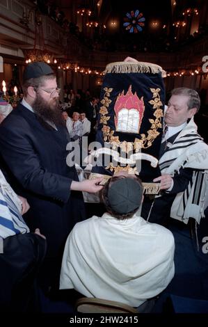 Die neue Sefer Tora wird um die Synagoge getragen, damit die Gemeinde ihre Achtung zollt. Der Oberrabbiner Jonathan Sacks war Ehrengast für die Aufnahme der letzten Briefe in eine neue Sefer-Torah in der Synagoge der hebräischen Kongregation Singers Hill am Sonntag, dem 15. März 1998. Mitglieder der Gemeinde sowie der Oberrabbiner fügten jeweils einen einzigen Brief hinzu. Stockfoto