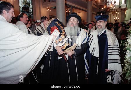 Die neue Sefer Tora wird um die Synagoge getragen, damit die Gemeinde ihre Achtung zollt. Der Oberrabbiner Jonathan Sacks war Ehrengast für die Aufnahme der letzten Briefe in eine neue Sefer-Torah in der Synagoge der hebräischen Kongregation Singers Hill am Sonntag, dem 15. März 1998. Mitglieder der Gemeinde sowie der Oberrabbiner fügten jeweils einen einzigen Brief hinzu. Stockfoto