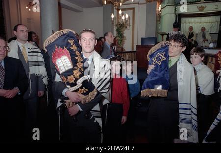 Die neue Sefer Tora wird um die Synagoge getragen, damit die Gemeinde ihre Achtung zollt. Der Oberrabbiner Jonathan Sacks war Ehrengast für die Aufnahme der letzten Briefe in eine neue Sefer-Torah in der Synagoge der hebräischen Kongregation Singers Hill am Sonntag, dem 15. März 1998. Mitglieder der Gemeinde sowie der Oberrabbiner fügten jeweils einen einzigen Brief hinzu. Stockfoto