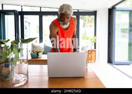afroamerikanischer bärtiger älterer Mann mit Laptop, der Yoga über Online-Tutorial lernt Stockfoto