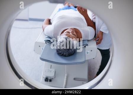 Scanvorgang wird vorbereitet. Aufnahme einer älteren Frau, die zuvor von einem Arzt getröstet wurde, und einer MRT-Untersuchung. Stockfoto