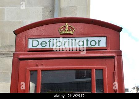 Nahaufnahme von leuchtend roten alten Telefonzellen draußen. Vintage, Britische, Königliche Telefonzellen für Defibrillator im Notfall, Herzinfarkt, Stockfoto
