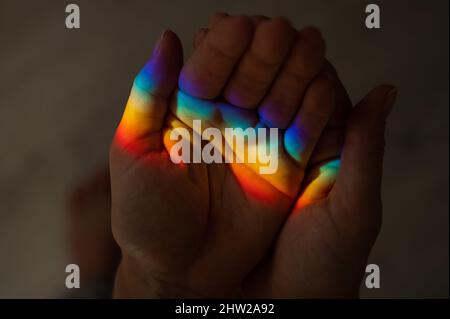 Regenbogenstrahl auf der Hand einer Frau. Stockfoto