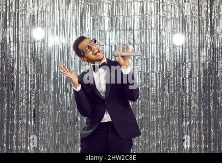 Lächelnder schwarzer Mann singt Karaoke im Mikrofon Stockfoto