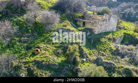 Ruinen eines verlassenen alten Steinhauses ohne Dach in einem traditionellen Dorf in mediterraner Landschaft Stockfoto