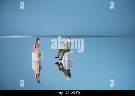 Einige Miniaturmenschen in Beziehung zueinander auf einer Spiegelfläche Stockfoto