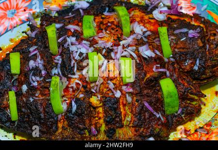 Gegrillter Fisch, Seebrasse mit Zusatz von Gewürzen, Kräutern und Zitrone auf der Grillplatte. Stockfoto