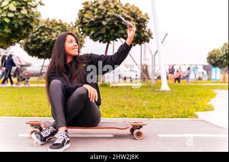 Schöne Skater Mädchen nimmt ein Selfie im Park Stockfoto