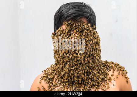 Imker von Bienen bedeckt, hat er die Bienenkönigin am Hals, so dass alle Bienen an seinem Körper haften. surrealismus Stockfoto
