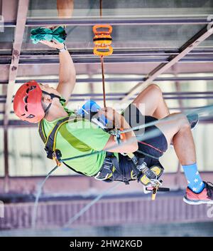 Arbeiter beim Bergsteigen waschen Glasfenster des Hochhauses, hängen an einem Kletterseil. Man Fensterputzer in Schutzhelm Reinigung Wolkenkratzer Fassade. Draufsicht. Stockfoto