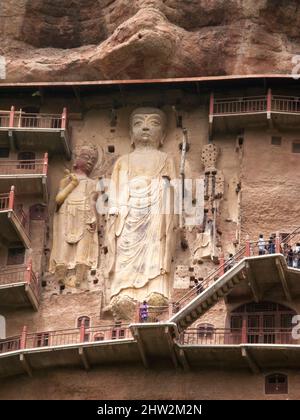 Buddha stellt Darstellungen und buddhistische Bilder dar (die erst vor kurzem mit Beton restauriert wurden) auf der Felswand der Maijishan-Grotten, die früher als Maichishan romanisiert wurden, eine Serie von 194 Höhlen, die an der Seite des Hügels von Majishan in Tianshui, Provinz Gansu, China, geschnitten wurden. Treppen und Gehwege sind an der schieren Felswand angebracht, um den Besuchern einen engen Kontakt mit den Tonfiguren und alten Steinschnitzereien an der Stelle zu ermöglichen. (67/125) Stockfoto