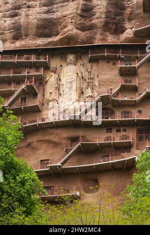 Stufen und Gehwege, die an der schieren Felswand befestigt sind, ermöglichen es den Besuchern, die alten geschnitzten Statuen des buddhistischen Tages zu sehen, an dem sie befestigt und in die Steinoberfläche der Felswand gehauen ist. Die Maijishan-Grotten, früher als Maichishan romanisiert, Sind eine Reihe von 194 Höhlen, die an der Seite des Hügels von Majishan in Tianshui, Provinz Gansu, China, geschnitten wurden. (67/125) Stockfoto