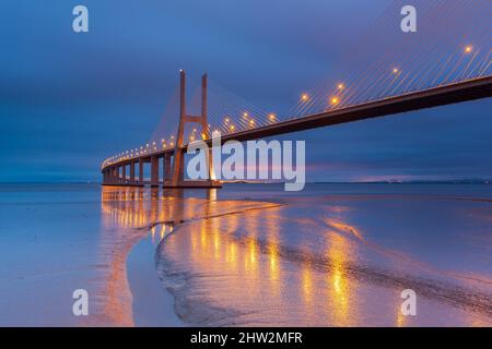 Nachtlichter auf der Lissabon-Brücke. Die Vasco da Gama Brücke ist ein Wahrzeichen und eine der längsten Brücken der Welt. Stadtlandschaft. Portugal ist ein Stockfoto