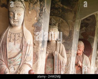 Stufen und Gehwege, die an der schieren Felswand befestigt sind, ermöglichen es den Besuchern, die alten geschnitzten Statuen des buddhistischen Tages zu sehen, an dem sie befestigt und in die Steinoberfläche der Felswand gehauen ist. Die Maijishan-Grotten, früher als Maichishan romanisiert, Sind eine Reihe von 194 Höhlen, die an der Seite des Hügels von Majishan in Tianshui, Provinz Gansu, China, geschnitten wurden. (67/125) Stockfoto