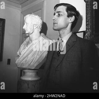 1960s, historical, Merlin Charles Sainthill Hanbury-Tracy, 7. Baron Sudeley, The Lord Sudeley steht neben einer Marmorbüste seines Vorfahren Charles Hanbury-Tracy, 4. Baron Sudeley. Der ehrenwerte Baron von 4., ein liberaler Politiker, war berühmt für sein gotisches Herrenhaus, das Toddington Manor, das teilweise als Vorbild für die Houses of Parliament gilt, als sie in den Jahren 1840s nach einem Brand erbaut wurden. Stockfoto