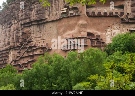 Stufen und Gehwege, die an der schieren Felswand befestigt sind, ermöglichen es den Besuchern, die alten Lehmstatuen von Buddha und die Statue buddhistischer Gottheiten zu sehen, die an der Steinoberfläche der Felswand angebracht und geschnitzt sind.die Maijishan-Grotten, früher als Maichishan romanisiert, Sind eine Reihe von 194 Höhlen, die an der Seite des Hügels von Majishan in Tianshui, Provinz Gansu, China, geschnitten wurden. (67/125) Stockfoto