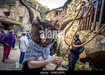 Ein Foliao tanzt mit einer Pitchfork in seinen Händen. Im portugiesischen Dorf Gois, im Bezirk Coimbra, durchquert während des Karnevals eine Gruppe von Menschen namens ìfolioesî mit ihren Korkmasken mehrere Schieferdörfer, erzählt Witze über die Dorfbewohner, quält die älteren Damen und verführt die jüngsten. Stockfoto