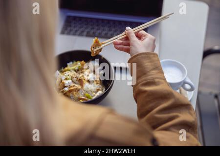 Nahaufnahme einer Frau, die Lebensmittel mit Essstäbchen hält Stockfoto