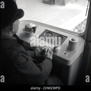 1968, historisch, ein U-Bahnfahrer in Mütze und Jacke, sitzt in der Fahrerkabine einer U-Bahn-Station der Londoner U-Bahn, London, England, Großbritannien. Er drückt zwei Tasten, um den Zug zu starten, danach übernimmt er automatisch die Kontrolle. Die Züge, die als Bestand von 1967 bekannt sind, fuhren erstmals 1968 auf der neu eröffneten Victoria-Linie und waren bis 2011 im Einsatz. Ausgestattet mit dem Automatic Train Operation (ATO)-System waren sie die ersten automatischen Eisenbahnzüge der Welt. Sie waren auch das erste rollende Material der Londoner U-Bahn mit Rundum-Fenstern in der Fahrerkabine. Stockfoto