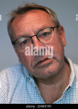 Kopf- und Schulterportrait eines 60-jährigen Mannes mit Lesebrille und Blick auf die Kamera Stockfoto
