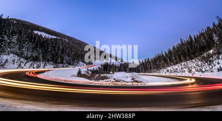 Die Lichter der Autos verschwimmen, während die Geschwindigkeit um eine Haarnadel auf dem Berthoud Pass in der Nähe von Winter Park, Colorado, abbiegt Stockfoto